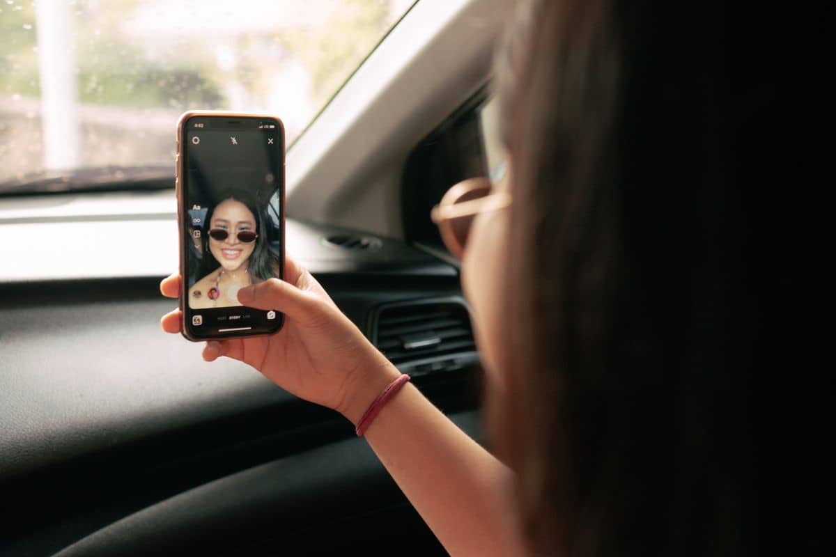 A woman is taking a selfie with her phone in the car.