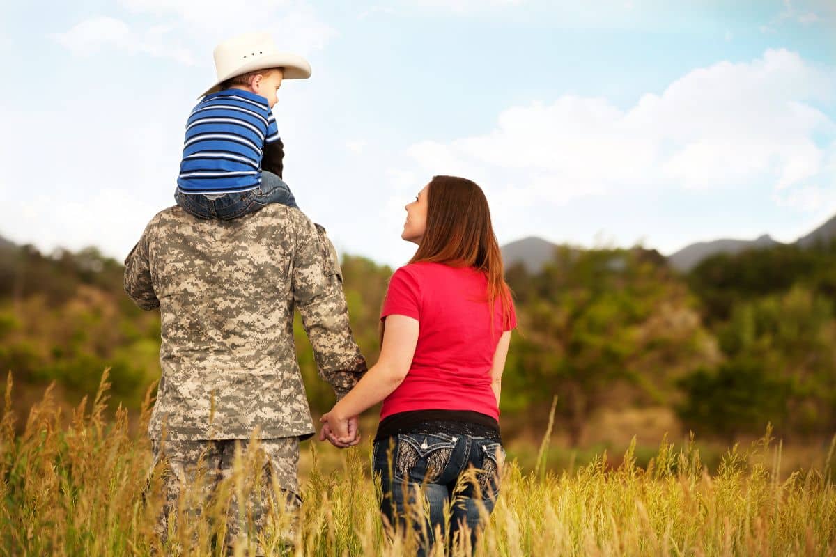 A woman and her son are holding hands in a field.