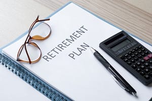 A retirement plan with glasses and a calculator on a desk.